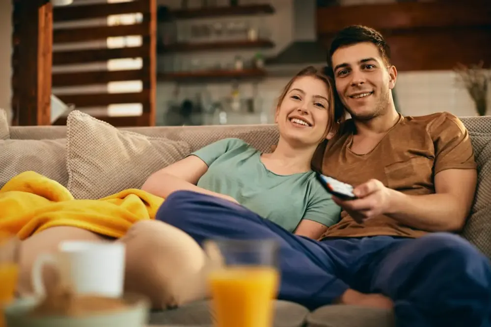 Couple détendu sur le canapé devant la télévision avec son abonnement IPTV
